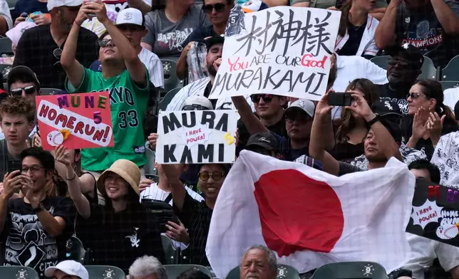 Fans of Chicago White Sox's Munetaka Murakami of Japan, hold signs and a Japanese flag during the first inning of a baseball game between the Houston Astros and the Chicago White Sox in Chicago, Sunday, July 26, 2026. (AP Photo/Nam Y. Huh)