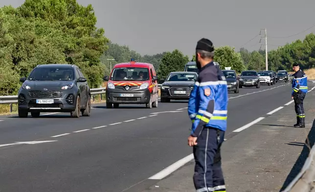 People leave the Ares region during wildfires, western France, Friday July 24, 2026. (AP Photo/Caroline Blumberg)