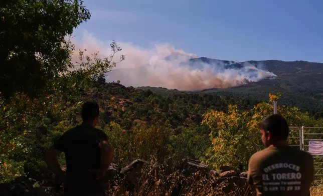 Smoke and flames rise as a wildfire advances near Burgohondo, Ávila province, Spain, Friday, July 24, 2026. (AP Photo/Manu Fernandez)