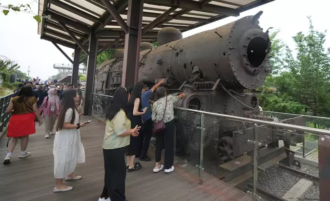 Tourists look at a steam train that was damaged during the Korean War, is displayed at the Imjingak Pavilion in Paju, South Korea, Saturday, July 4, 2026. (AP Photo/Lee Jin-man)
