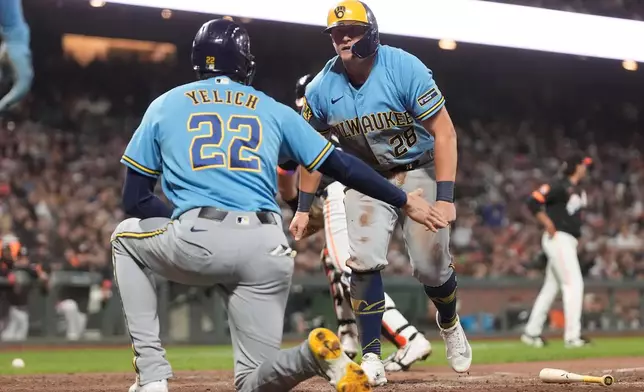Milwaukee Brewers' Christian Yelich (22) celebrates with Andrew Vaughn (28) after both scored on a two-run triple hit by Luis Lara during the seventh inning of a baseball game against the San Francisco Giants, Tuesday, July 28, 2026, in San Francisco. (AP Photo/Jeff Chiu)