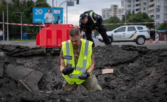 A sapper examines the impact site of a Russian missile in a residential area of Kyiv, Saturday, July 11, 2026. (AP Photo/Dan Bashakov)