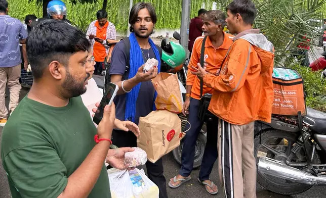 A protestor receives a food package from a supporter at the site where thousands have assembled to join a protest called by Cockroach Janta Party in New Delhi, India, Wednesday, July 22, 2026. (AP Photo/Piyush Nagpal)