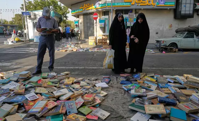 People look at books which are placed for sale on a street in downtown Tehran, Iran, Saturday, July 18, 2026. (AP Photo/Vahid Salemi)