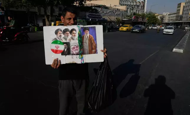 A man displays a placard with portraits of the current and late supreme leaders and the late Revolutionary Guard Gen. Qassem Soleimani at the Islamic Revolution Square in downtown Tehran, Iran, Saturday, July 18, 2026. (AP Photo/Vahid Salemi)