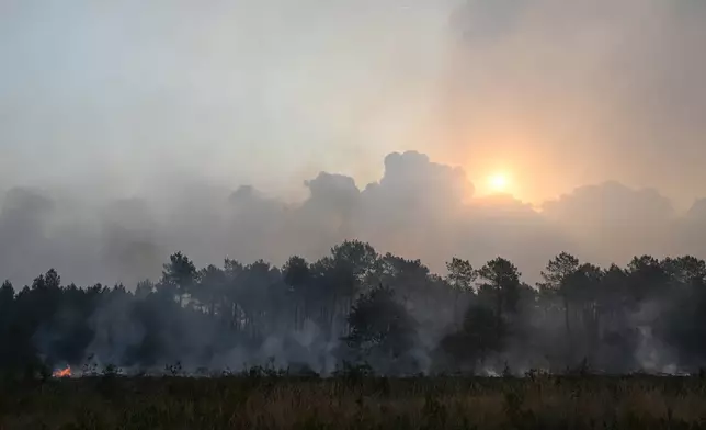 The rising sun appears through smoke from burning wildfires near Marcheprime, outside Bordeaux, France, Sunday, July 26, 2026. (AP Photo/Emma Da Silva)