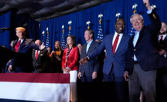 FILE - Republican presidential candidate former President Donald Trump speaks as Sen. Tim Scott, R-S.C., and Sen. Lindsey Graham, R-S.C., listen, at a primary election night party at the South Carolina State Fairgrounds in Columbia, S.C., Feb. 24, 2024. (AP Photo/Andrew Harnik, File)