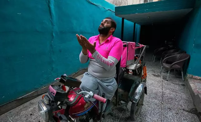 Hamza Ali, 28, who lost both legs in a road accident, prays before leaving for work in Islamabad, Pakistan, Friday, July 17, 2026. (AP Photo/Anjum Naveed)