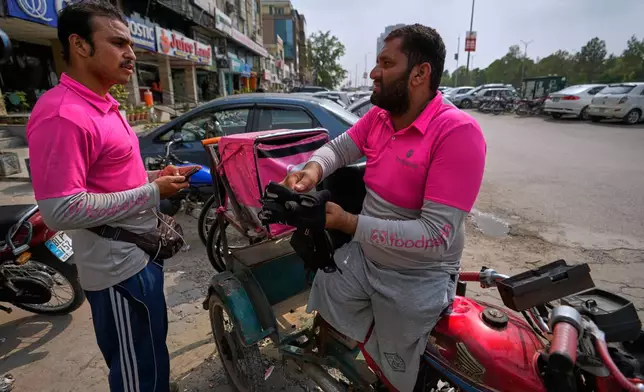 Hamza Ali, 28, who lost both legs in a road accident, speaks with a colleague as he leaves for a delivery order in Islamabad, Pakistan, Friday, July 17, 2026. (AP Photo/Anjum Naveed)