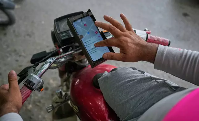 Hamza Ali, 28, who lost both legs in a road accident, uses a mobile app to communicate with a customer for a food delivery order in Islamabad, Pakistan, Friday, July 17, 2026. (AP Photo/Anjum Naveed)
