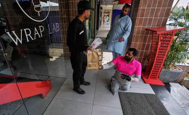 Hamza Ali, 28, who lost both legs in a road accident, collects a meal order from a food outlet to deliver to a customer in Islamabad, Pakistan, Friday, July 17, 2026. (AP Photo/Anjum Naveed)