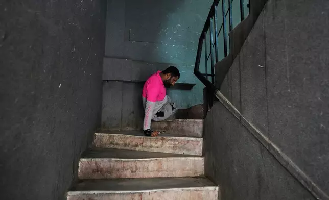 Hamza Ali, 28, who lost both legs in a road accident, moves up a flight of stairs to deliver food to a customer in Islamabad, Pakistan, Friday, July 17, 2026. (AP Photo/Anjum Naveed)