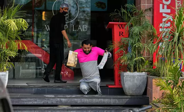 Hamza Ali, 28, who lost both legs in a road accident, leaves after collecting a meal order for delivery in Islamabad, Pakistan, Friday, July 17, 2026. (AP Photo/Anjum Naveed)