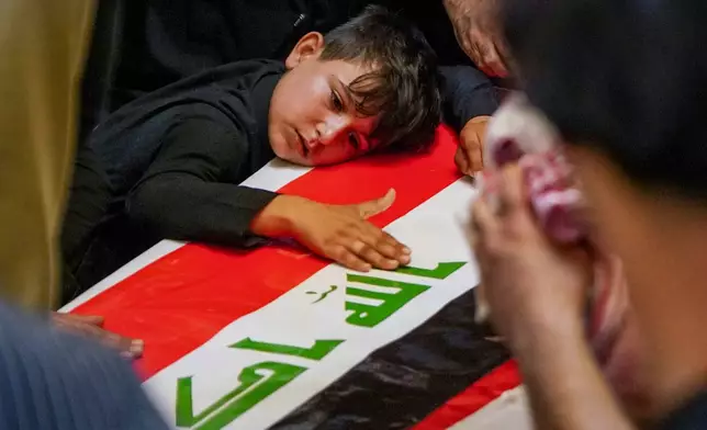 A child rests his head on the coffin of a Popular Mobilization Forces fighter draped in the Iraqi flag during a funeral for Popular Mobilization Forces fighters killed in airstrikes on PMF bases in Najaf, Iraq, Thursday, July 30, 2026. (AP Photo/Anmar Khalil)