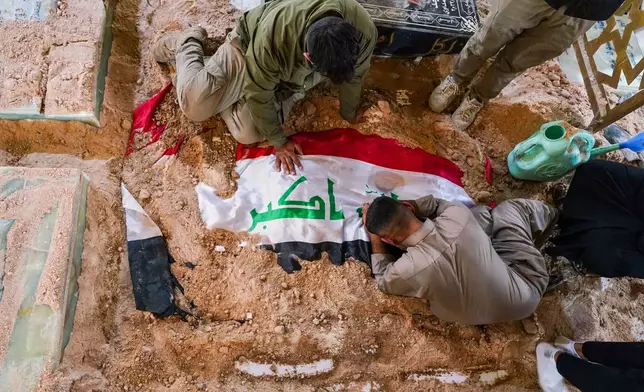 Mourners grieve at the grave of a Popular Mobilization Forces fighter during a funeral for fighters killed in airstrikes on PMF bases in Najaf, Iraq, Thursday, July 30, 2026. (AP Photo/Anmar Khalil)