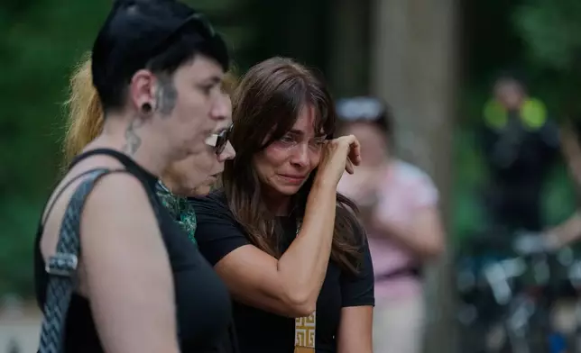 People attend the memorial site commemorating the victims near the scene where a car rammed into a crowd near the Pride March in Berlin, Germany, Sunday, July 26, 2026. (AP Photo/Markus Schreiber)