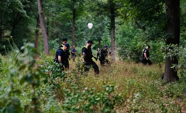 A police officer searches in the Tiergarten Park near the scene where a vehicle rammed into a crowd near the Pride March in Berlin, Germany, Sunday, July 26, 2026. (AP Photo/Markus Schreiber)