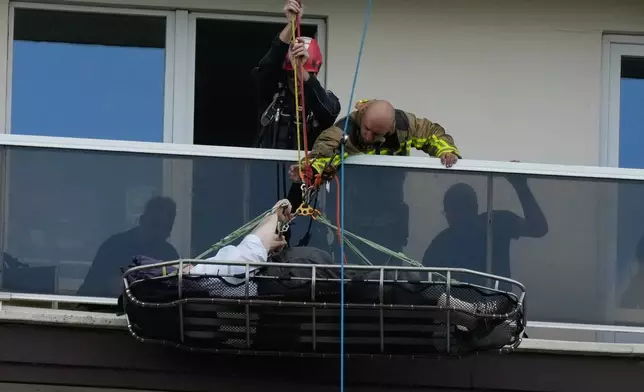 A person is evacuated from an upper floor after an apartment block fire in Linkeroever, Belgium, Wednesday, July 1, 2026. (AP Photo/Virginia Mayo)