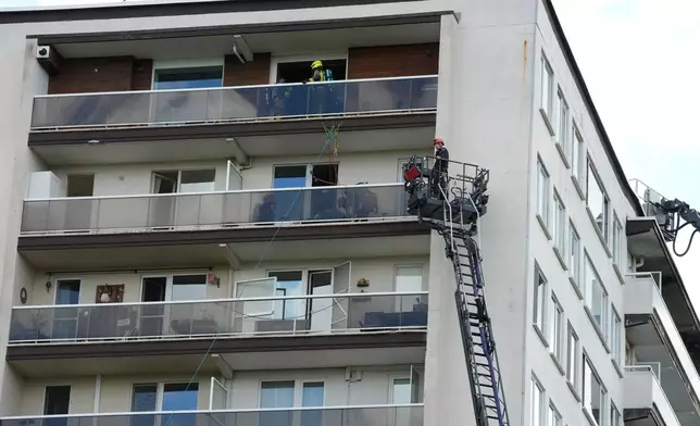 Rescue workers look for victims on upper floors after an apartment block fire in Linkeroever, Belgium, Wednesday, July 1, 2026. (AP Photo/Virginia Mayo)