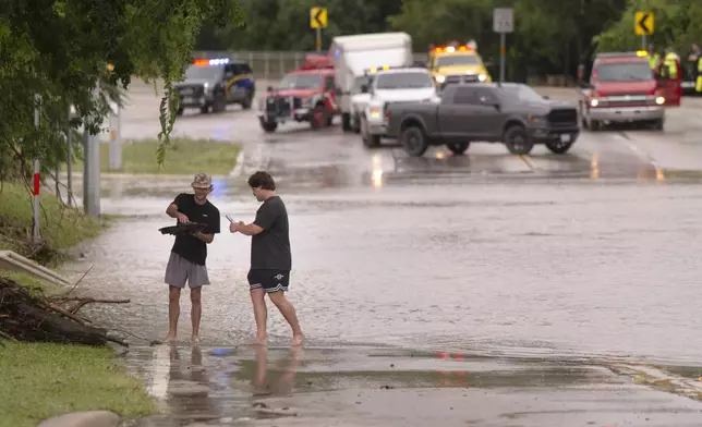 Reece Noble, left, and Gavyn Steffek, photograph a tortoise they found in flood waters on Wednesday, July 15, 2026, in Boerne, Texas. (AP Photo/Darren Abate)