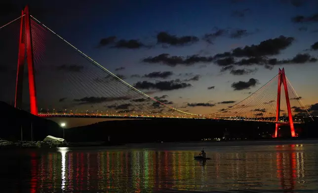 A man paddles in the Bosphorus Strait near the Yavuz Sultan Selim bridge after sunset in Istanbul, Turkey, Thursday, June 18, 2026. (AP Photo/Emrah Gurel)