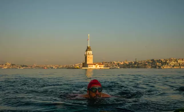 Erdem Sahin swims in the Bosphorus Strait, backdropped by the Maiden's tower, during the early morning in Istanbul, Turkey, Thursday, July 2, 2026. (AP Photo/Emrah Gurel)