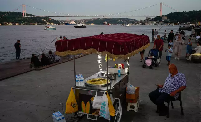 A vendor sells corn on the bank of the Bosphorus Strait at dusk in Istanbul, Turkey, Friday, June 26, 2026. (AP Photo/Emrah Gurel)