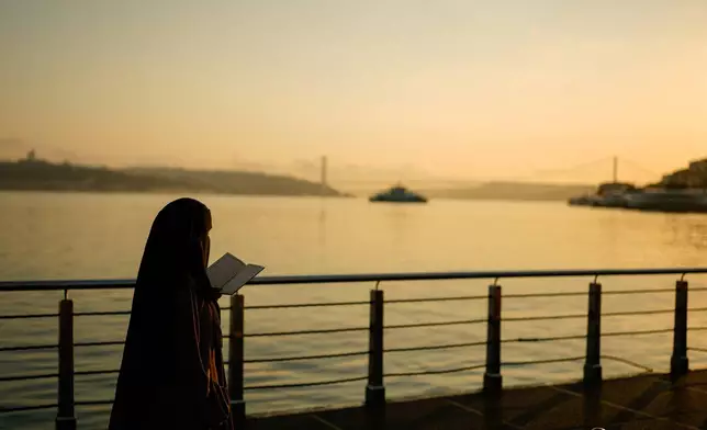 A woman reads the Quran along the Bosphorus Strait at sunrsise in Istanbul, Turkey, Thursday, July 2, 2026. (AP Photo/Emrah Gurel)