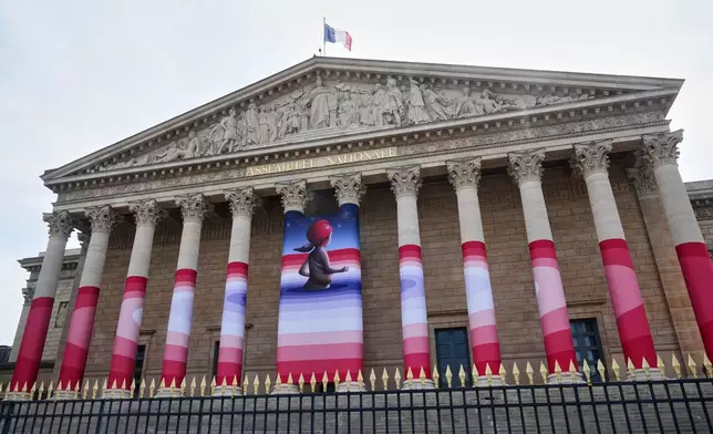 The French National Assembly is draped with the artwork "Marianne rêve" ("Marianne Dreams") by French street artist Seth, depicting Marianne the symbol of the French Republic, before lawmakers vote later on final approval of a bill allowing adults with incurable illnesses to receive lethal medication, in Paris, Wednesday, July 15, 2026. (AP Photo/Michel Euler)