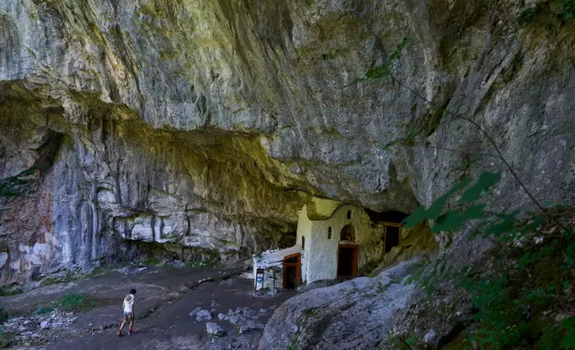 A visitor approaches a chapel at the Holy Cave of St. Dionysios in the Enipeas Gorge on Mount Olympus in northern Greece, Tuesday, July 14, 2026. (AP Photo/Petros Giannakouris)