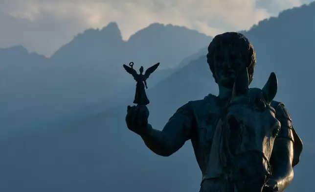A statue of Alexander the Great holding Nike, the Greek goddess of victory, stands near Litochoro in northern Greece, Tuesday, July 14, 2026, backdropped by Mount Olympus' highest peaks, Mytikas and Stefani. (AP Photo/Petros Giannakouris)