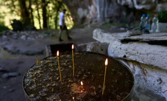 Candles burn outside a chapel at the Holy Cave of St. Dionysios in the Enipeas Gorge on Mount Olympus in northern Greece, Tuesday, July 14, 2026. (AP Photo/Petros Giannakouris)