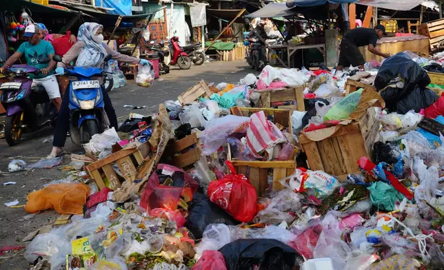 A woman throws a bag of trash onto an open garbage dump in Jakarta, Indonesia, Friday, July 17, 2026. (AP Photo/Tatan Syuflana)
