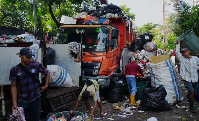 Workers load garbage onto a truck at temporary waste disposal site in Jakarta, Indonesia Friday, July 17, 2026. (AP Photo/Tatan Syuflana)