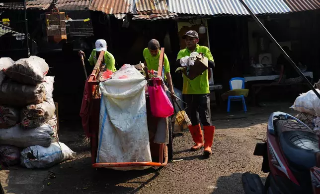 Sanitation workers collect trash at a traditional market in Jakarta, Indonesia, Friday, July 17, 2026. (AP Photo/Tatan Syuflana)