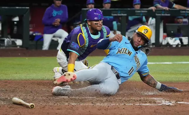 Milwaukee Brewers' Jackson Chourio (11) scores a run in front of Arizona Diamondbacks catcher Gabriel Moreno on a ball hit by Brice Turang in the eleventh inning of a baseball game, Friday, July 3, 2026, in Phoenix. (AP Photo/Rick Scuteri)