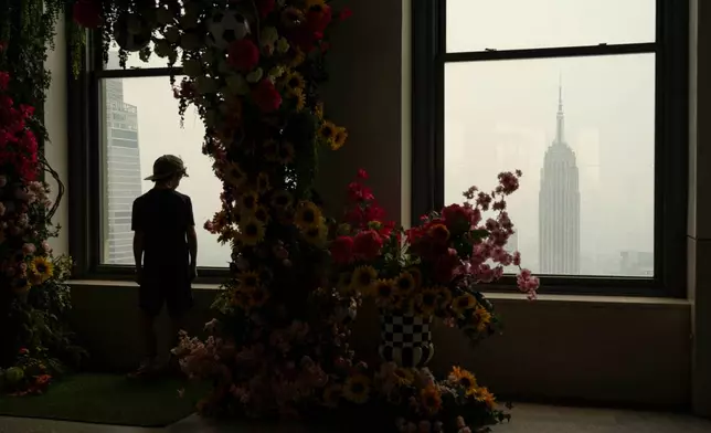 A person looks out a window at the Top of the Rock Observation Deck as wildfire smoke hangs over New York, Thursday, July 16, 2026. (AP Photo/Yuki Iwamura)