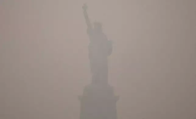 The Statue of Liberty stands during sunset as smoke from wildfires blankets the sky, Thursday, July 16, 2026, in the Brooklyn borough of New York. (AP Photo/Yuki Iwamura)