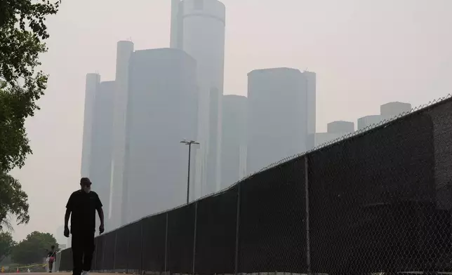 Jimmy Tyner walks along the Detroit River during poor air quality due to smoke from Canadian wildfires Thursday, July 16, 2026, in Detroit. (AP Photo/Paul Sancya)