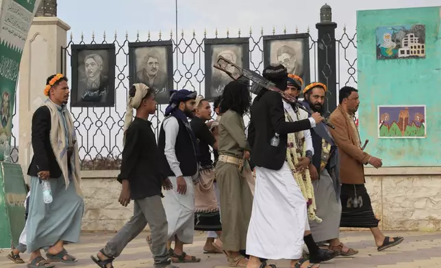 Houthi supporters walk in front of posters of some top Iranian scientists who have been killed in Israeli strikes, in Sanaa, Yemen, Monday, July 13, 2026. (AP Photo/Osamah Abdulrahman)