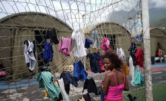 Nataly Mayora hangs clothes to dry on a soccer goal net as she does laundry at a sports center sheltering people displaced by the earthquakes in La Guaira, Venezuela, Thursday, July 9, 2026. (AP Photo/Ariana Cubillos)