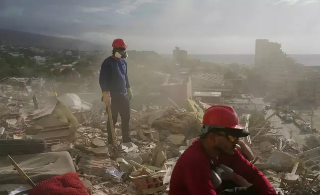 Rescue workers and volunteers search through the rubble of a building collapsed during the earthquakes in La Guaira, Venezuela, Monday, July 6, 2026. (AP Photo/Ariana Cubillos)