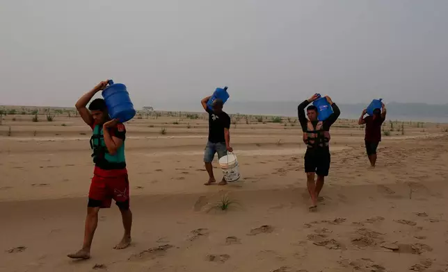 FILE - Residents transport drinking water from Humaita to the Paraizinho community, along a dry part of the Madeira River, a tributary of the Amazon River, amid a drought, Amazonas state, Brazil, Sep. 8, 2024. (AP Photo/Edmar Barros, File)
