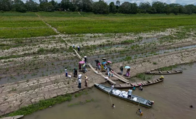 FILE - People from the Tikuna Indigenous receive aid from an NGO because of the drought along the Amazon River in Santa Sofia, on the outskirts of Leticia, Colombia, Oct. 20, 2024. (AP Photo/Ivan Valencia, File)