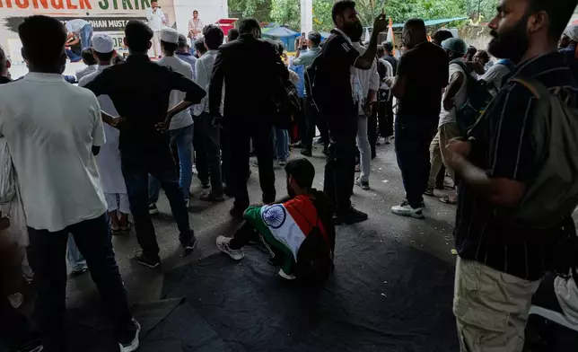 A supporter with Indian flag on his shoulder sits and listen to a speaker with others during a protest by the Cockroach Janta Party demanding the resignation of Education Minister Dharmendra Pradhan over alleged examination irregularities and repeated paper leaks, in New Delhi, India, on July 10, 2026. (AP Photo/Manish Swarup)