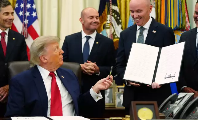 President Donald Trump hands a pen to Utah Gov. Spencer Cox after signing executive orders modifying the Grand Staircase-Escalante National Monument and the Bears Ears National Monument in the Oval Office of the White House, Monday, July 13, 2026, in Washington. (AP Photo/Julia Demaree Nikhinson)