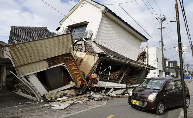 A vehicle passes by collapsed houses after an earthquake in Yatsushiro, Kumamoto prefecture, Wednesday, July 29, 2026.(Juntaro Yokoyama/Kyodo News via AP)