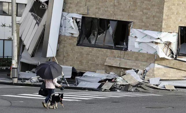 People walk a dog past a building collapsed by an earthquake in Yatsushiro, Kumamoto prefecture, Wednesday, July 29, 2026.(Juntaro Yokoyama/Kyodo News via AP)