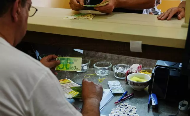 A currency exchange employee counts Israeli Shekels at a bureau in the West Bank city of Bethlehem, Tuesday, July 7, 2026. (AP Photo/Mahmoud Illean)