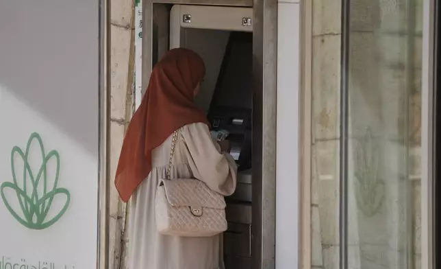 A Palestinian woman withdraws money from an ATM in the West Bank city of Bethlehem, Tuesday, July 7, 2026. (AP Photo/Mahmoud Illean)